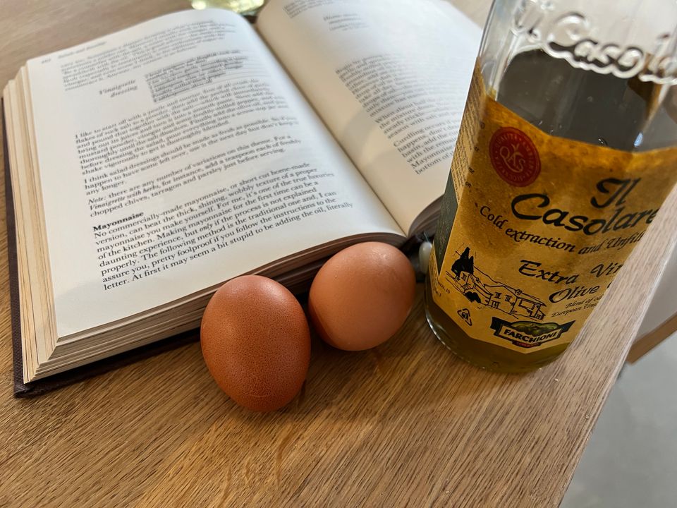 Delia Smith's recipe book open at the Mayonnaise recipe, with eggs and oil in the foreground